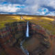 a view from above of Hengifoss waterfall surrounded by basalt columns mixed with bands of red clay