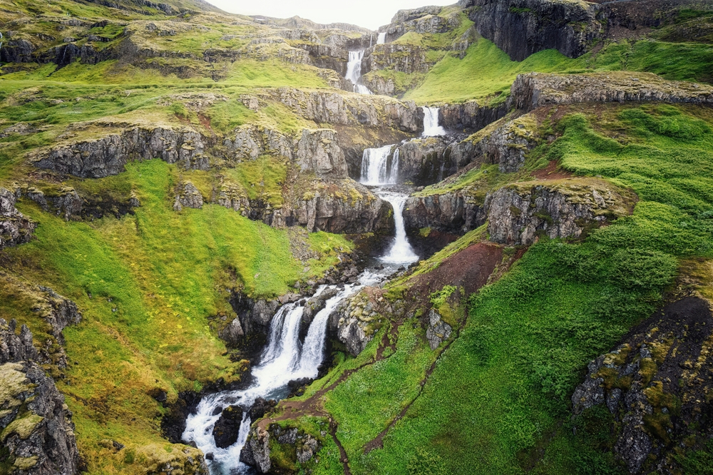 the seven tiers of Klifbrekkufossar streaming down the lush green cliffs