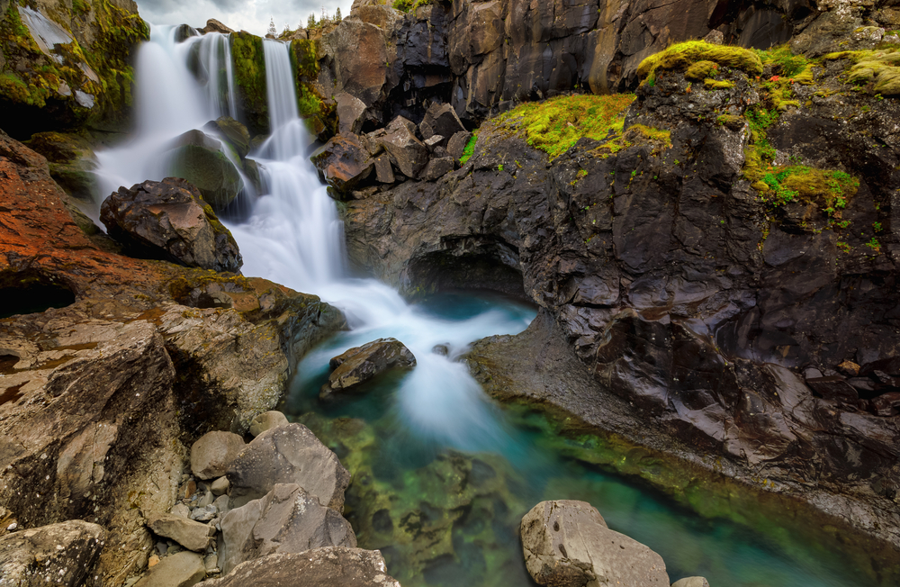 Nykurhylsfoss, one of the best waterfalls in east iceland, streaming down into the Fossá River, flanked by moss covered cliffs