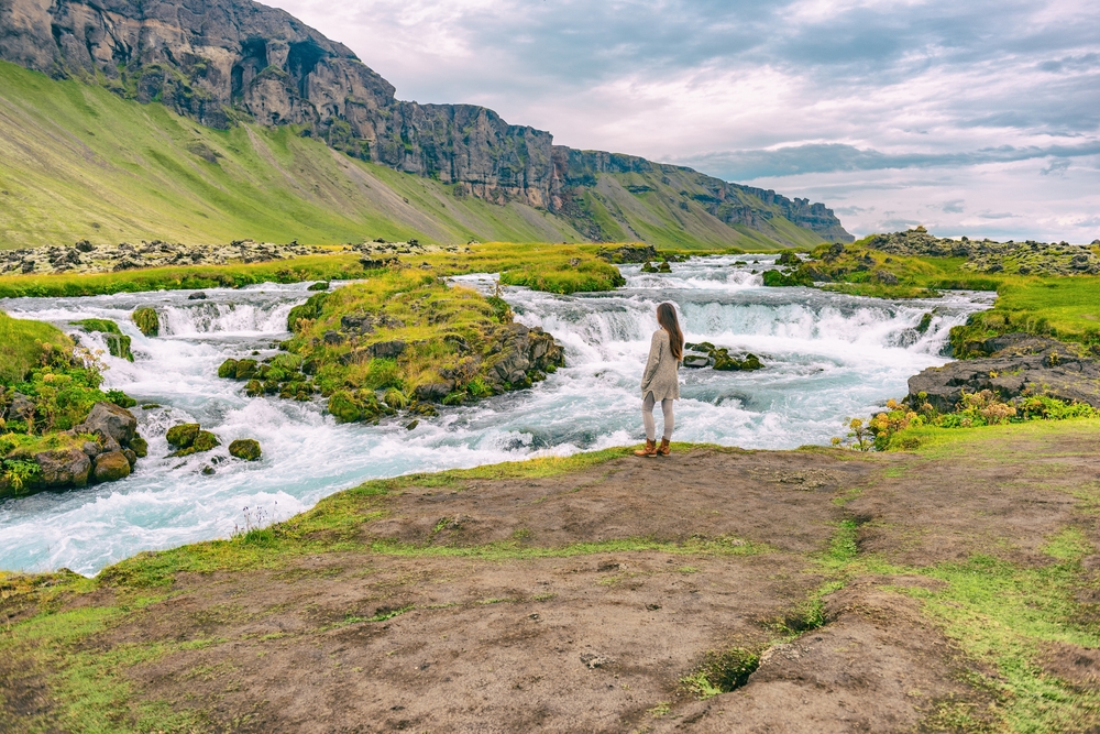 When wondering what to wear in Iceland in June, choose comfort and style like this model: as she stands on the edge of rushing ground water, her hiking boots and matching fleece set have her prepared during her road trip. 