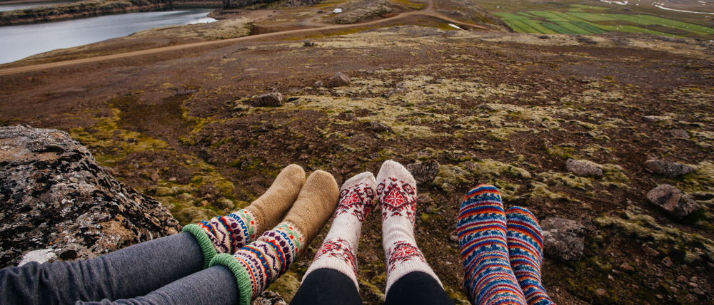 A pair of girls show their feet against the cool land and how they are covered in thermal leggings and wool socks.