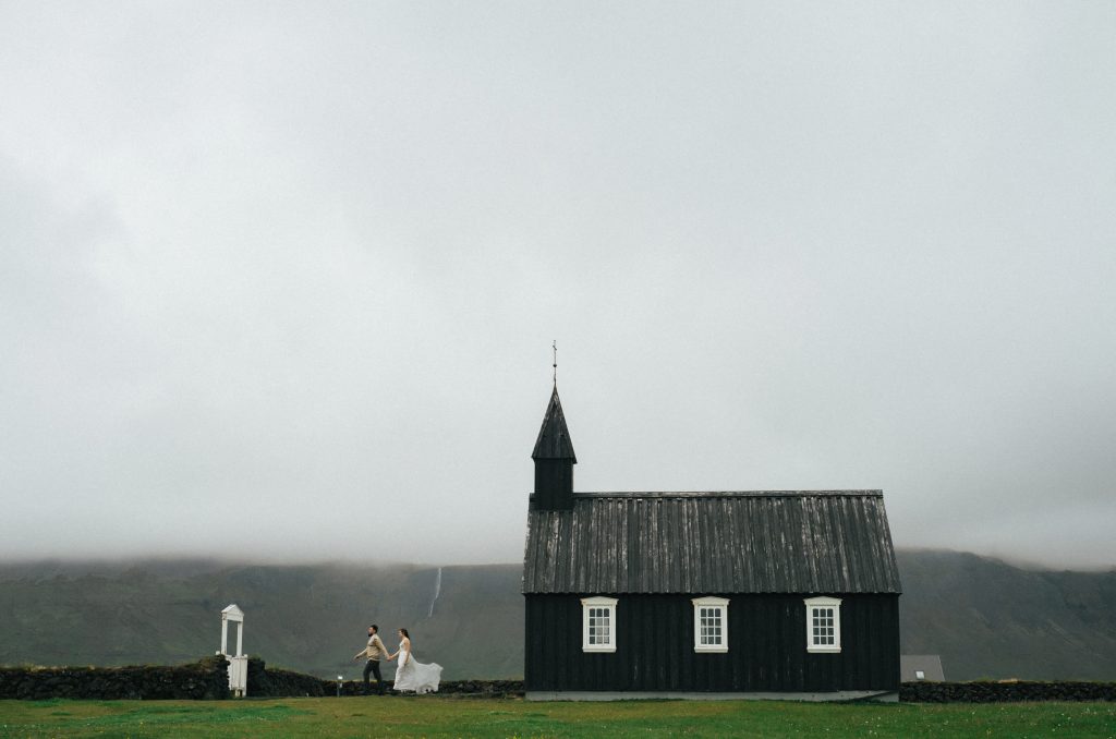 This tiny black church rising from a lava field is moody Iceland at its finest as a married couple walks out of the church